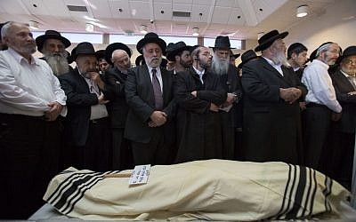 Mourners standing next to the body of Shalom Aharon Ba'adani during his funeral in Jerusalem on November 7, 2014. Ba'adani died Friday after being injured when a terrorist rammed his minivan into a crowd waiting for a train in Jerusalem on November 5. (Photo credit: Yonatan Sindel/Flash90)