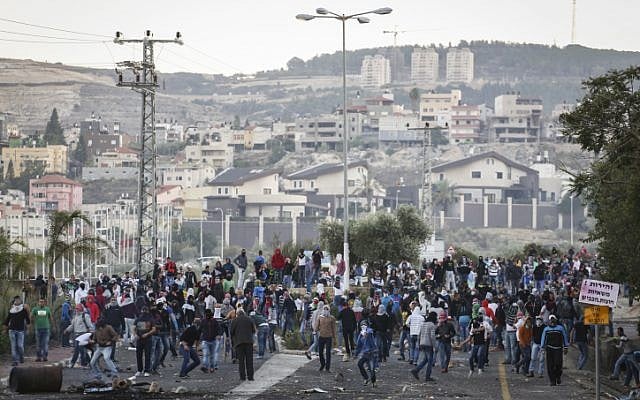 Israeli Arabs seen waving Palestinian and Hamas flags and throwing rocks towards Israeli border policemen at the entrance to the Arab village of Kafr Kanna in northern Israel, on November 8, 2014. (photo credit: Hadas Parush/Flash90) Israeli Arabs seen waving Palestinian and Hamas flags and throwing rocks towards Israeli border policemen at the entrance to the Arab village of Kafr Kanna in northern Israel, on November 8, 2014. (photo credit: Hadas Parush/Flash90)