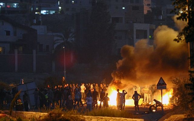 Palestinian youth seen throwing rocks towards Israeli Border Policemen at the entrance to the Arab village, Kfar Kanna, in Northern Israel, on November 9, 2014. (photo credit: Flash90) Palestinian youth seen throwing rocks towards Israeli Border Policemen at the entrance to the Arab village, Kfar Kanna, in Northern Israel, on November 9, 2014. (photo credit: Flash90)