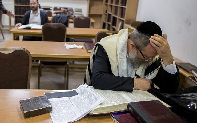 An ultra-Orthodox man peers over a Talmud in the Jerusalem synagogue where five people were killed a day earlier. November 19, 2014. (photo credit: Yonatan Sindel/Flash90)
