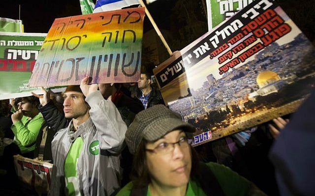 Left wing activists holding placards and flags as they protest against the "Jewish state" bill near the Prime Minister residence in Jerusalem on November 29, 2014. (Photo by Yonatan Sindel/Flash90)
