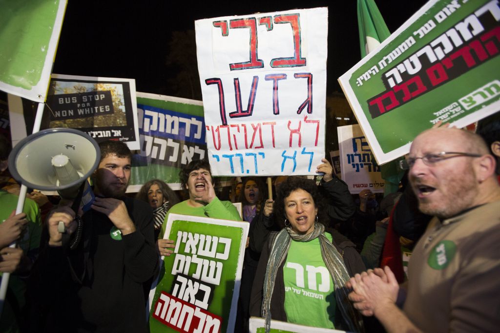 Left-wing activists hold placards and flags as they protest against the "Jewish state" bill near the Prime Minister residence in Jerusalem on November 29, 2014. Some of the placards call Benjamin Netanyahu a racist, and assert that he seeks democracy for Jews only. (Photo credit: Yonatan Sindel/Flash90) Left-wing activists hold placards and flags as they protest against the "Jewish state" bill near the Prime Minister residence in Jerusalem on November 29, 2014. Some of the placards call Benjamin Netanyahu a racist, and assert that he seeks democracy for Jews only. (Photo credit: Yonatan Sindel/Flash90)