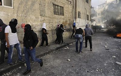 In this Thursday, Oct. 30, 2014 file photo, Palestinian youths throw stones during clashes with Israeli border police after Mu'taz Hijazi, suspected of trying to kill a  Jewish activist, was killed in east Jerusalem.  (Photo credit: AP/Mahmoud Illean, File)