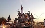 Militants from the Islamic State parade in a commandeered Iraqi security forces armored vehicle on a main street in Mosul, Iraq, Monday, June 23, 2014. (photo credit: AP, File)