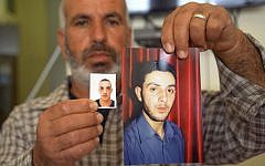 A relative displays photos of cousins Ghassan, right, and Uday Abu Jamal at the family home in the East Jerusalem neighborhood of Jabel Mukaber, Tuesday Nov. 18, 2014 (photo credit: AP/Mahmoud Illean)