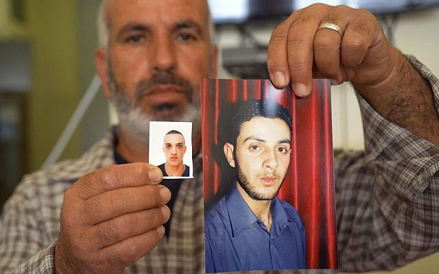 A relative displays photos of cousins Ghassan, right, and Uday Abu Jamal at the family home in the East Jerusalem neighborhood of Jabel Mukaber, Tuesday Nov. 18, 2014 (photo credit: AP/Mahmoud Illean)