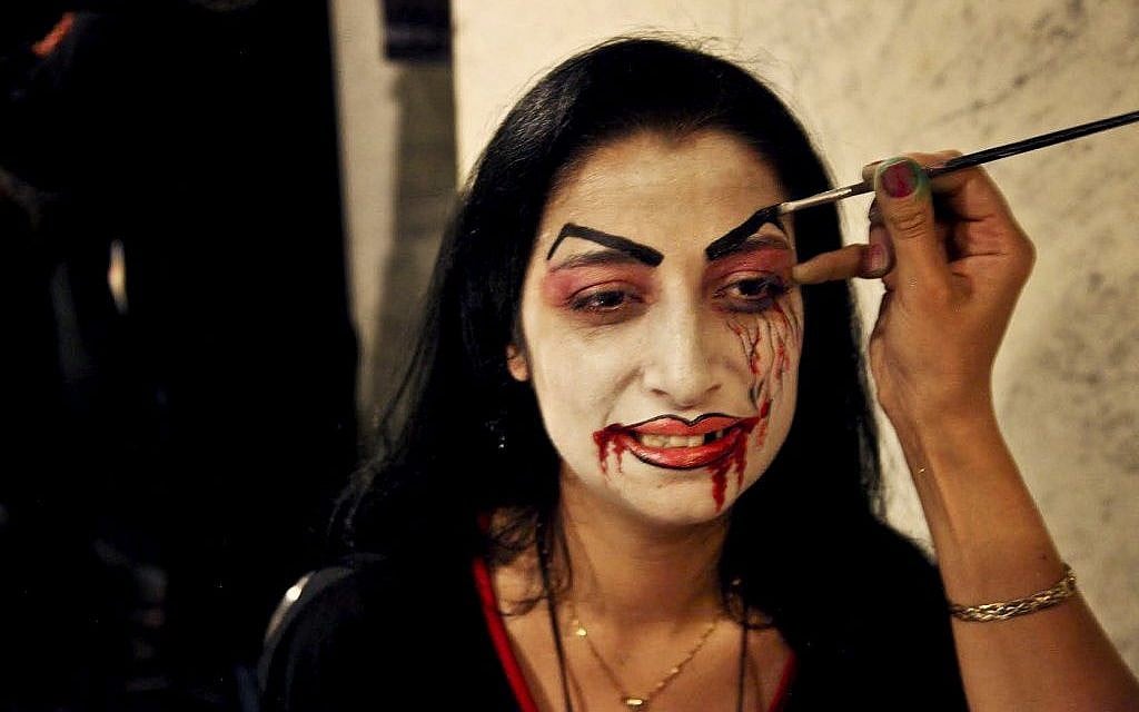 In this Thursday, Oct. 30, 2014, photo, a woman gets her face painted before entering a Halloween party in an upscale Damascus hotel. Amid a conflict grinding well into its fourth year, Syrians have sought to deny war its miserable monotony by taking pleasure in mindless entertainment, ranging from lounging in cafes, to dancing to thumping discos. (photo credit: AP Photo/Diaa Hadid) In this Thursday, Oct. 30, 2014, photo, a woman gets her face painted before entering a Halloween party in an upscale Damascus hotel. Amid a conflict grinding well into its fourth year, Syrians have sought to deny war its miserable monotony by taking pleasure in mindless entertainment, ranging from lounging in cafes, to dancing to thumping discos. (photo credit: AP Photo/Diaa Hadid)