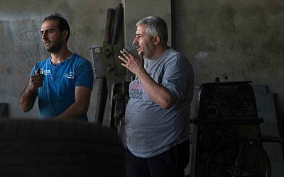 In this Tuesday, October 28, 2014 photo, Mohammed Jallad, 32, left, speaks to another worker in an industrial workshop in the coastal Syrian city of Tartous. (photo credit: AP Photo/Diaa Hadid)