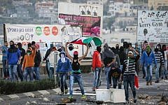 Arab youth seen waving the Palestinian flag and throwing rocks towards Border Police at the entrance to the Arab village Kafr Kanna, November 8, 2014. (Hadas Parush/Flash90)