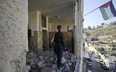 Palestinians hang their national flag inside the demolished apartment of Abdel Rahman al-Shaludi in East Jerusalem, November 19, 2014. (photo credit: AP Photo/Mahmoud Illean, File)
