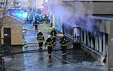 Smoke rises from the interior of a destroyed cellar mosque as firefighters walk in front of the building after an arson attack on December 25, 2014 in Eskilstuna, central Sweden. An arsonist set fire to the mosque in central Sweden on Thursday injuring five, police said, as the country faces a deep political crisis caused by the rise of the extreme right. (AFP/ TT News Agency /Pontus Stenberg)