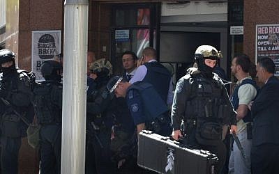 Armed police are seen outside a cafe in the central business district of Sydney on December 15, 2014. Hostages were being held inside a cafe in central Sydney on December 15 with an Islamic flag displayed against a window, according to witnesses and reports. (Photo credit: AFP/Peter Parks)