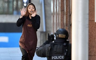 One of the hostages runs toward police from a cafe in Sydney on December 15, 2014. (photo credit: AFP/SAEED KHAN) One of the hostages runs toward police from a cafe in Sydney on December 15, 2014. (photo credit: AFP/SAEED KHAN)