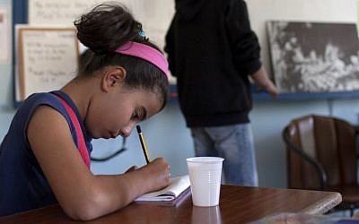 A young Syrian refugee takes notes as she listens to her English teacher during a class at the American Academy in the Cypriot capital Nicosia on November 11, 2014. (AFP/FLORIAN CHOBLET)