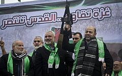 Gaza Hamas leaders Ismail Haniya, center, and Mousa Abu Marzouq, right, brandish a weapon as they greet supporters during a parade marking the 27th anniversary of the Islamist movement’s creation on December 14, 2014 in Gaza City. (AFP/MAHMUD HAMS)