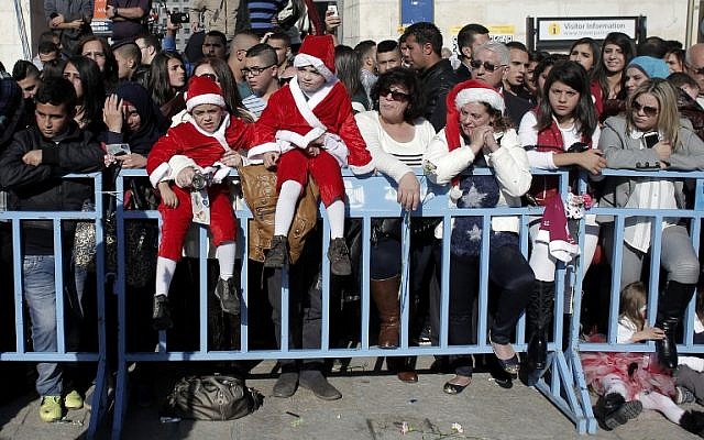 People gather to watch Christmas celebrations in Manger Square outside the Church of the Nativity as Christians gather for Christmas celebrations in the West Bank city of Bethlehem on December 24, 2014. (AFP PHOTO/AHMAD GHARABLI)