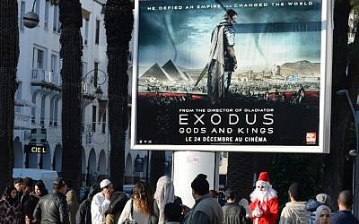 A man dressed as Santa Claus stands next to a billboard for the Hollywood biblical epic movie "Exodus: Gods and Kings" displayed in the Moroccan capital Rabat on December 26, 2014. photo credit: AFP/FADEL SENNA)