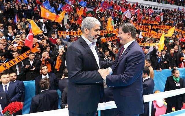 A handout made available by the Turkish Prime Minister's Press office on December 27, 2014, shows senior Hamas leader Khaled Mashaal (L) shaking hands with Turkish Prime Minister Ahmet Davutoglu. (photo credit: AFP PHOTO / HO / PM OFFICE / HAKAN GOKTEPE)