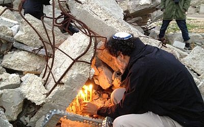 Rabbi Arik Ascherman, president of Rabbis for Human Rights, lights Hannukah candles on the ruins of a demolished home in the village of Dirat in the Southern West Bank, December 22, 2014 (photo credit: Elhanan Miller/Times of Israel)