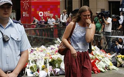 A woman cries after laying a flower at a makeshift memorial in Sydney, Australia Tuesday, Dec. 16, 2014 near where three people died in a siege. (photo credit: AP Photo/Nick Perry)
