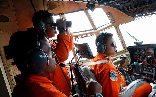 Crew of Indonesian Air Force C-130 airplane of the 31st Air Squadron scan the horizon during a search operation for the missing AirAsia flight 8501 jetliner over the waters of Karimata Strait in Indonesia, Monday, Dec. 29, 2014. (AP Photo/Dita Alangkara)