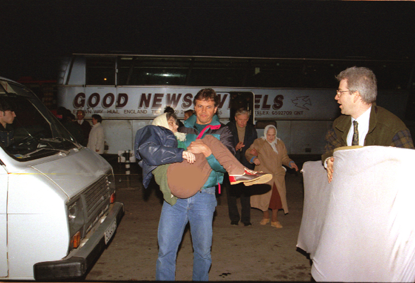 Former International Christian Embassy international director Michael Utterback assists a disabled Russian Jew from a bus onto a plane for the flight to Israel. It is a literal fulfillment of Isaiah 49:22-23, which speaks of God using gentiles to bring the sons and daughters of Israel home 'in their arms' in 1992. (courtesy)