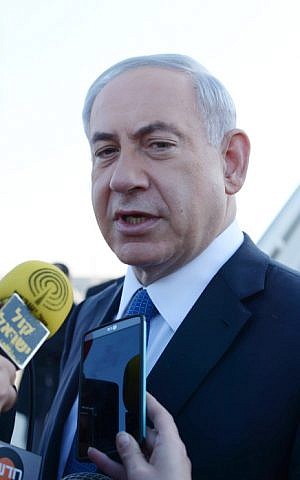 Benjamin Netanyahu speaks with the media before boarding a plane to Rome at Ben-Gurion Airport, outside of Tel Aviv, December 15, 2014. (Photo credit: Amos Ben Gershom/GPO)