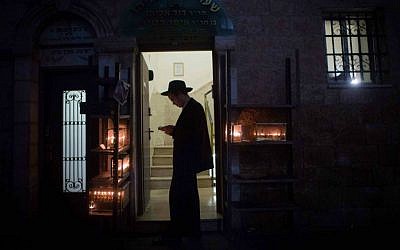 An ultra-Orthodox Jewish man lights candles for the Jewish holiday of Hanukkah in the poor, ultra-Orthodox Jerusalem neighborhood of Mea Shearim, December 23, 2014. (Yonatan Sindel/Flash90)