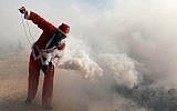 A Palestinian protester wearing a Santa Claus costume holds a tear gas canister during a protest against Israel's security barrier outside the West Bank village of Bil'in, near Ramallah, Friday, December 26, 2014 (photo credit: STR/Flash90)