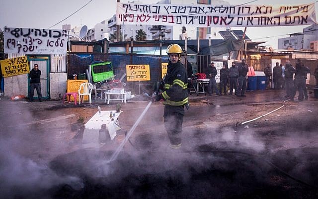 A firefighter puts out a fire started by Givat Amal residents on December 29, 2014. (photo credit: Amir Levi/Flash90)