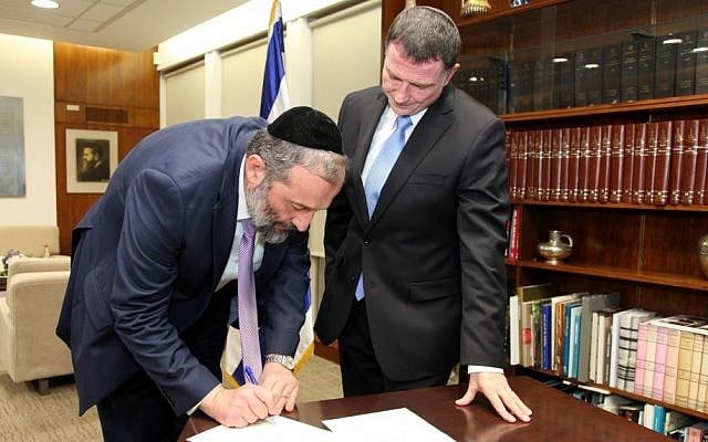 Shas party leader Aryeh Deri signs a letter resigning from the Knesset, as Speaker Yuli Edelstein looks on, December 30, 2014. (Photo credit: Isaac Harari/Knesset Spokesperson)