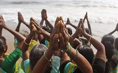 Indian women offer prayers on the Marina Beach at the Bay of Bengal to commemorate the 10th anniversary of the 2004 Tsunami in Chennai, India, Friday, Dec. 26, 2014. (Photo credit: AP/Arun Sankar K)