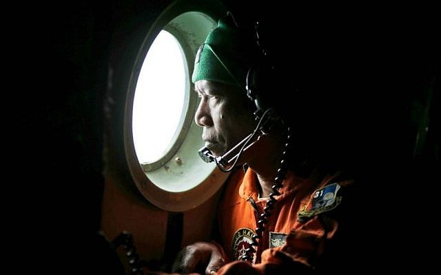 A crew of an Indonesian Air Force C-130 airplane of the 31st Air Squadron looks out of the window during a search operation for the missing AirAsia flight 8501 jetliner over the waters of Karimata Strait in Indonesia, Monday, Dec. 29, 2014. (AP Photo/Dita Alangkara)