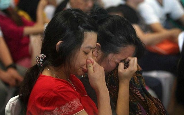 Relatives and next-of-kin of passengers on the AirAsia flight QZ8501 wait, some in tears while others in prayer, for the latest news on the search of the missing jetliner at Juanda International Airport in Surabaya, East Java, Indonesia, Monday, Dec. 29, 2014. (AP Photo/Trisnadi Marjan)