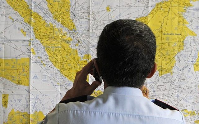 An airport official checks a map of Indonesia at the crisis center set up by local authority for the missing AirAsia flight QZ8501, at Juanda International Airport in Surabaya, East Java, Indonesia, Sunday, Dec. 28, 2014.  (photo credit: AP/Trisnadi)