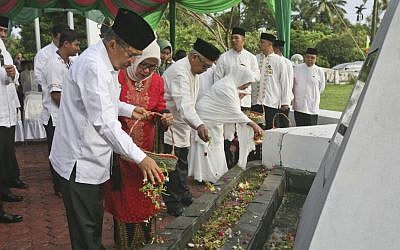Indonesian Vice President Jusuf Kalla sprinkles flowers during a ceremony commemorating the 10th anniversary of the Indian Ocean tsunami at a mass grave in Aceh Besar, Aceh province, Indonesia, Friday, Dec. 26, 2014. (Photo credit: AP/Binsar Bakkara)
