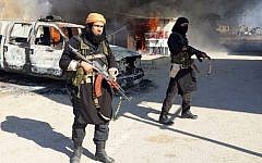 This undated file image posted on a militant website on January 4, 2014, which is consistent with other AP reporting, shows Shakir Waheib, a senior member of the Islamic State of Iraq and the Levant (ISIL), now called the Islamic State group, left, next to a burning police vehicle in Iraq's Anbar Province. (Photo credit: AP via militant website, File)