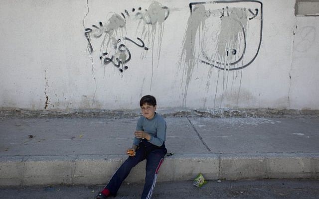 A Jordanian boy sits on the sidewalk by painted-over graffiti depicting the flag of the Islamic State group with Arabic that reads "their is only one God and Muhammad is his prophet, the Islamic state is staying," October 29, 2014. (AP/Nasser Nasser) A Jordanian boy sits on the sidewalk by painted-over graffiti depicting the flag of the Islamic State group with Arabic that reads "their is only one God and Muhammad is his prophet, the Islamic state is staying," October 29, 2014. (AP/Nasser Nasser)