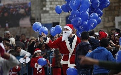 A Palestinian dressed as Santa Claus holds balloons at Manger Square, outside the Church of the Nativity, traditionally believed by Christians to be the birthplace of Jesus, in the West Bank city of Bethlehem on Christmas Eve, December 24, 2014. (AP Photo/Majdi Mohammed/File)