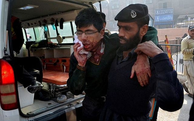 A hospital security guard helps a student injured in the shootout at a school under attack by Taliban gunmen in Peshawar, Pakistan,Tuesday, Dec. 16, 2014. (photo credit: AP/Mohammad Sajjad)