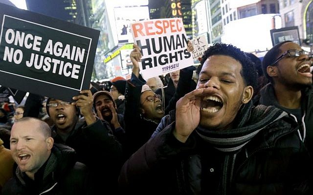 Protesters shout in Times Square after the announcement that the New York City police officer involved in the death of Eric Garner is not being indicted, December 3, 2014. (photo credit: AP/Julio Cortez) Protesters shout in Times Square after the announcement that the New York City police officer involved in the death of Eric Garner is not being indicted, December 3, 2014. (photo credit: AP/Julio Cortez)