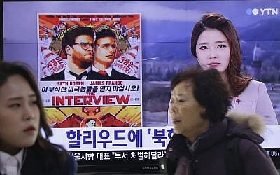 People walk past a TV screen showing a poster of Sony Picture's "The Interview" in a news report, at the Seoul Railway Station in Seoul, South Korea, Monday, Dec. 22, 2014. (Photo credit: AP/Ahn Young-joon)