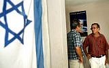 Illustrative: An Israeli flag hangs on the wall of the Jewish Community Center in Havana, Cuba, where two men are speaking on August 1, 2004. (Serge Attal/Flash90)