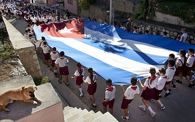 Young students carry a large Cuban flag, as they attend a parade through the streets of Gibara, Cuba. January 20, 2014. (photo credit: Moshe Shai/Flash90)