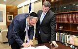 Shas party chairman Aryeh Deri (L) signing his official letter of resignation from the Knesset, December 30, 2014 (photo credit: Isaac Harari/Knesset Spokesperson)