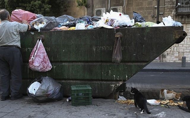 Illustrative photo of an Israeli man searching for objects of worth in a garbage container in the center of Jerusalem October 23, 2014. (Photo credit Nati Shohat/FLASH90)