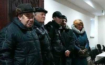 Members of the Lugansk Jewish community standing in front of their synagogue's Torah ark, Dec. 11, 2014. (Cnaan Liphshiz/JTA)