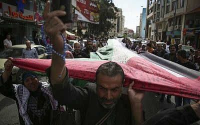 Palestinians activists march with a large Palestinian flag from Al Manara Square to the tomb of former Palestinian leader, Yasser Arafat, in central Ramallah, West Bank, October 28, 2014. The 66-meter long Palestinian flag, symbolizing 66 years since Israel's establishment, and signed by about 25,000 people, has entered the Guinness Book of Records. (photo credit: Hadas Parush/Flash90)