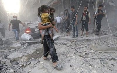 A Syrian man carries two girls covered with dust following a reported air strike by government forces on July 9, 2014 in the northern city of Aleppo. (Photo credit: AFP/AMC/ZEIN AL-RIFAI)
