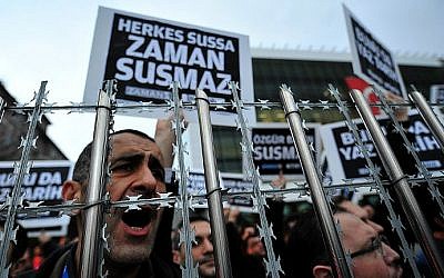 Staff members and supporters of Zaman newspaper shout slogans and hold placards reading "Free press can not be silenced" during a protest against a raid by counter-terror police in Istanbul on December 14, 2014 (photo credit: Ozan Kose / AFP) Staff members and supporters of Zaman newspaper shout slogans and hold placards reading "Free press can not be silenced" during a protest against a raid by counter-terror police in Istanbul on December 14, 2014 (photo credit: Ozan Kose / AFP)